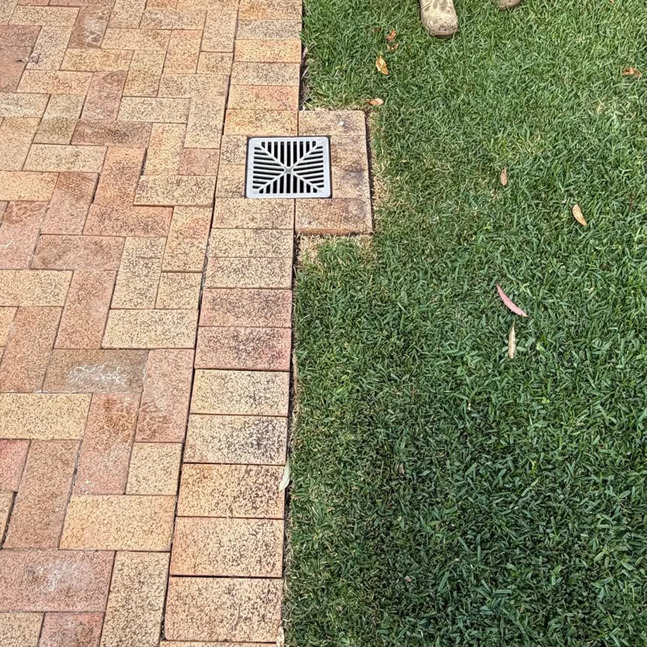 stormwater drain beside paving and grass